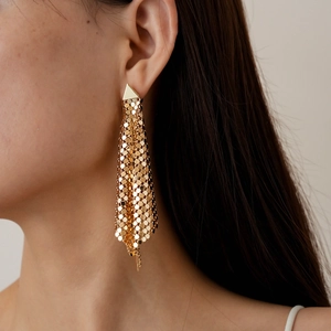 Close-up of golden metallic mesh tassel drop earrings with geometric diamond design