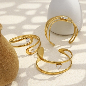 Artistic shadow play on three gold heart-shaped zircon bangles with shiny metal finish