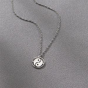 Polished stainless steel necklace featuring a circular Tai Chi Yin Yang pendant on gray surface