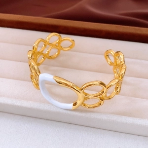 Detail of gold hollow bangle with white enamel inlay in a beige velvet jewelry box