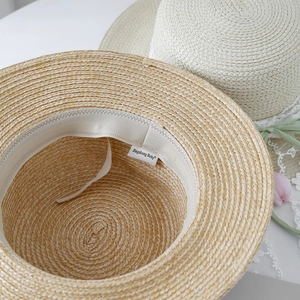 Handwoven straw sun hat for women featuring a flat top and delicate lace bow details