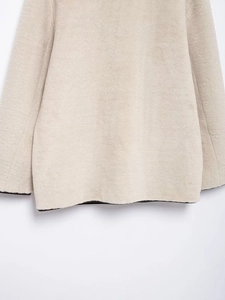 Dettaglio del cappotto in ecopelliccia beige chiaro con morbida trama su orlo e polsini