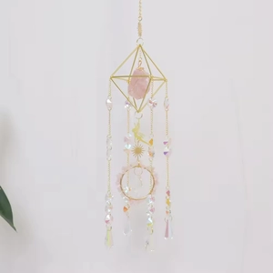 Detail of golden crystal suncatcher with pink raw stone and iridescent glass pendants