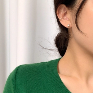 Detail of minimalist 925 silver ball studs and ear cuff worn by a model in green sweater