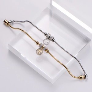 Close-up of gold and silver snake chain bracelets with crystal-set cross charms