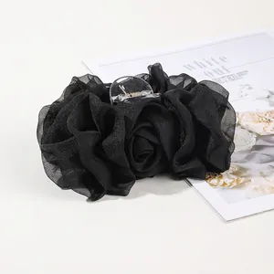 Detailed close-up of a large black chiffon flower hair claw clip with a plastic spring grip