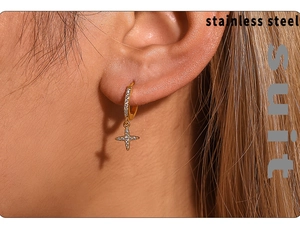 Close-up of gold stainless steel huggie hoop earrings featuring a pavé zircon star charm