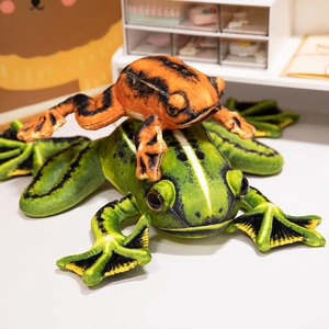 Plush green frog and small orange frog stuffed animals set on a white desk