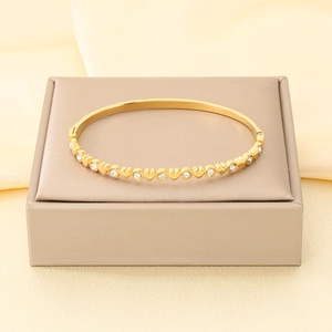 Vista dettagliata di un bracciale in acciaio inossidabile dorato con cuori e cristalli