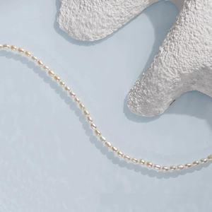 Macro detail of high-luster freshwater rice pearls on a minimalist blue background