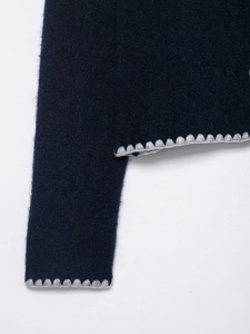 Detail shot of navy knit cardigan showing scalloped grey trim and wool texture