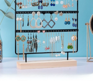 Three-layer black metal jewelry rack with wooden base holding various earrings