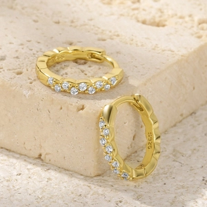 Macro shot of S925 sterling silver ear hoops with gold plating and wave pattern diamonds