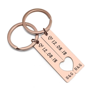 Close-up of rose gold rectangular couple keychains with a heart cutout and custom date