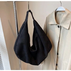Detailed texture of black suede tote bag hanging against a neutral background