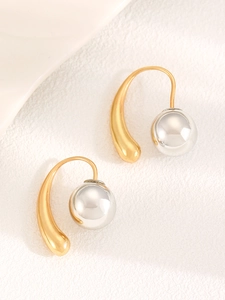 Detail of minimalist two-tone earrings featuring gold curved hooks and silver metal beads