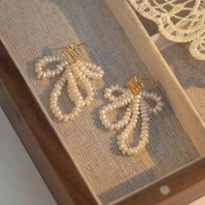 Close-up of bow-shaped pearl earrings in a jewelry box with elegant lace detail