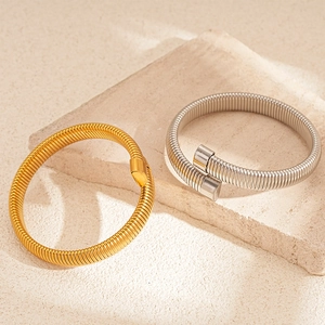 Chic snake-style elastic open bangles in gold and silver finish on a beige stone base