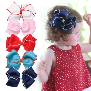 Five assorted colors of grosgrain ribbon bow hair clips for girls in a flat lay and model view
