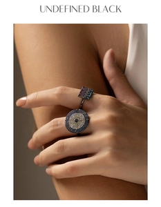 Close-up of black metal ring featuring pixel art evil eye and square motifs with crystals