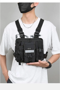 Detail of black tactical chest rig featuring multiple pockets and high-vis reflective strip