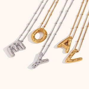 Macro detail of 3D puffy alphabet pendants in gold and silver finish with bead chains