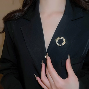 Macro shot of 18k gold plated pearl and zircon flower brooch on a black blazer