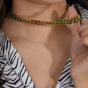 Close-up of a gold Cuban chain necklace with vibrant green enamel links on a model