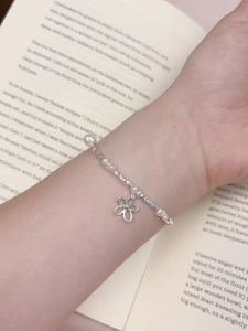 Detail of s925 silver flower charm bracelet with freshwater pearls on an open book