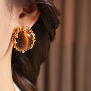 Detailed view of vintage gold-plated tiger eye stud earrings with textured borders