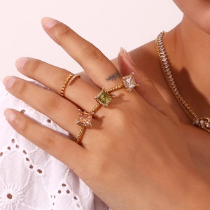 Close-up of 18K gold plated rings with pink and green gemstones on a model's hand