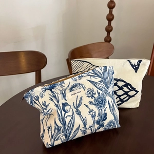 Artistic tie-dye canvas makeup bag with floral print and zipper closure on wooden table