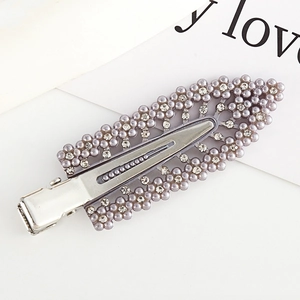 Detail of silver hair clip with purple pearls and rhinestones on a decorative card