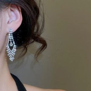 Detail of luxury rhinestone bow earrings shown on a model with elegant side view lighting
