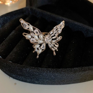 Detail of gold butterfly ring with white pearls and crystals on black velvet