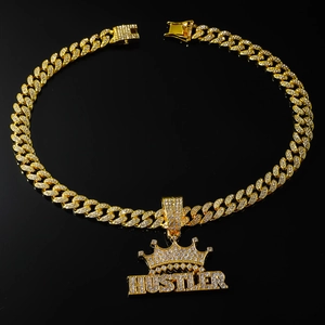 Gros plan du pendentif couronne HUSTLER doré serti de cristaux sur une chaîne cubaine