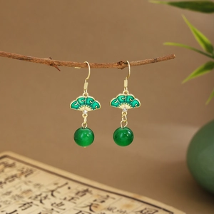 Detail of green fan-shaped earrings with bamboo leaf tassel hanging on a branch