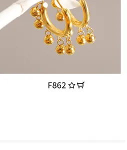 Detailed view of gold plated hoop earrings featuring polished bead charms on white branch