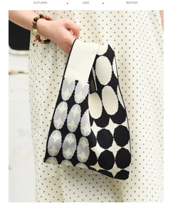 Close-up of a knitted tote bag with black and white geometric patterns held by a model