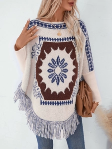Detail of bohemian knit poncho featuring geometric patterns and blue fringe tassels