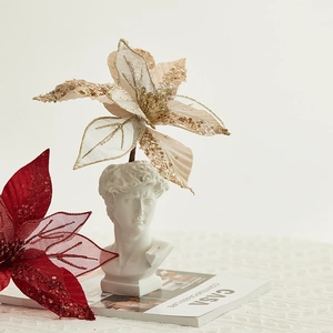 Golden and red sparkling artificial Christmas flowers on white plaster sculpture decor