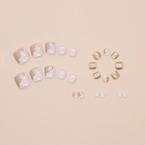 Macro detail of creamy white press-on toenails with glittering champagne gold ombre effect