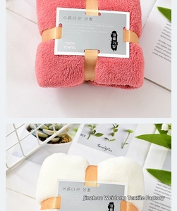 Macro view of thick coral fleece face towels in pink and white with golden ribbon