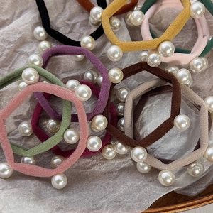 Close-up of assorted pearl elastic hair ties in vintage colors on a wooden tray