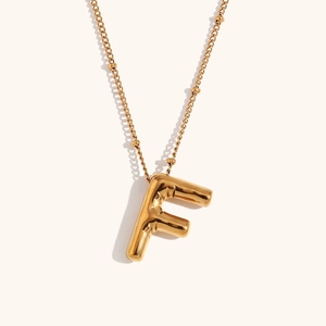 Detail of gold balloon letter F pendant on fine bead chain with polished 18K finish