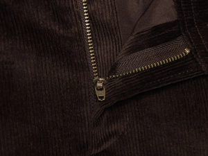 Close-up of brown corduroy fabric texture and high-quality bronze metal zipper detail
