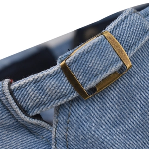 Rear view of a light blue denim beret featuring a vintage bronze metal adjustment buckle