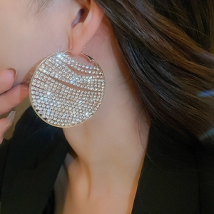 Close-up of oversized silver-tone hoop earrings with shimmering pavé rhinestones