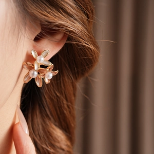 Close-up of floral earrings with gold plating, opal texture petals, and pearl centers