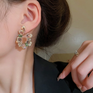 Dettaglio di orecchini a U oversize con cristalli ovali multicolore e pavé di zirconi